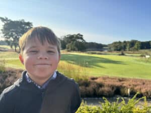 Jeugdige golfer met golfbaan op de achtergrond bij zonnig weer.