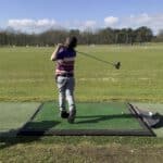 Jeugdgolfer slaat een bal tijdens een training op de driving range.