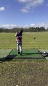 Jeugdgolfer slaat een bal tijdens een training op de driving range.