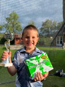 Trofee en doos golfballen vastgehouden door een jonge golfer.